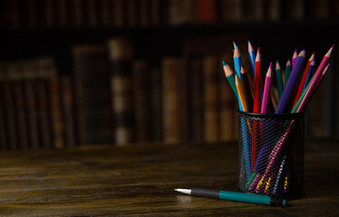 multi-colored pencils in a mesh glass on a dark background