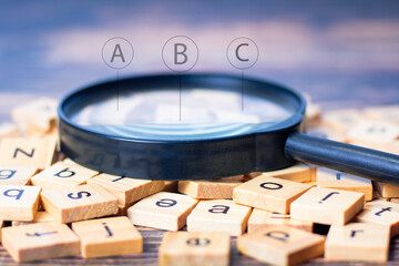 English letters are scattered on the table. The concept of developing grammatical ideas, English alphabet spreads with magnifying glass and English alphabet icons.