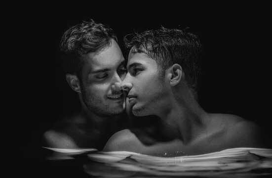 Gay Couple Relaxing In Swimming Pool. LGBT. Two Young Men Kissing And Hugging. Black And White Portrait. Handsome Young Male, Romantic Homosexual Family In Love. Happiness Concept, LGBTQ