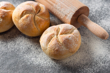 Set of small bun bread on the dark table with rolling pin. Fresh home baking concept