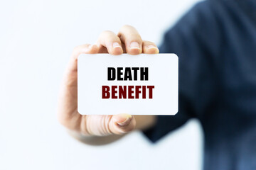 Death benefit text on blank business card being held by a woman's hand with blurred background. Business concept about death benefit.