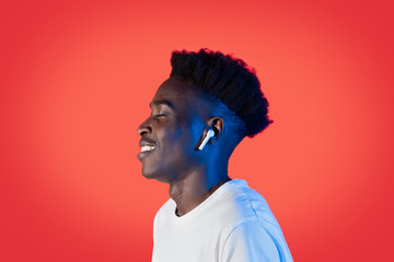 Happy black guy hipster listening to music, using wireless earpods