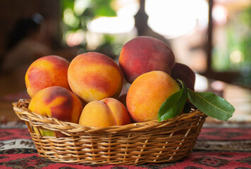 Ripe peaches fruits with leaves in basket on rustic background