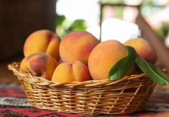 Fresh peaches fruits with leaves in basket on rustic background