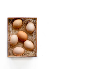 Fresh brown eggs and some straw in a wooden crate on a white background. Chicken eggs. Easter concept .Top view