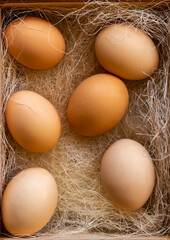 Fresh brown eggs and some straw in a wooden crate on a white background. Chicken eggs. Easter concept .