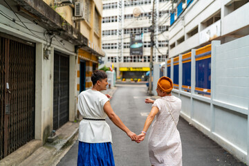 Asian drag queen gay friends in woman clothes and makeup walking down city street together on summer vacation. Diversity sexual equality, lgbtq pride people and transgender cross-dressing concept.