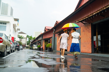 Asian drag queen gay friends in woman clothes holding umbrella walking down city street together in raining day. Diversity sexual equality, lgbtq pride people and transgender cross-dressing concept.