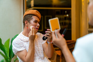 Two Asian guy drag queen friends in woman clothes applying makeup cosmetics together at coffee shop in the city. Diversity sexual equality, lgbtq pride people and transgender cross-dressing concept.