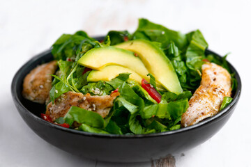 chicken salad with avocado in a black bowl. Healthy food