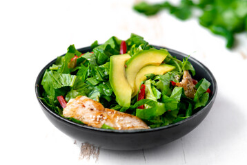 chicken salad with avocado in a black bowl. Healthy food