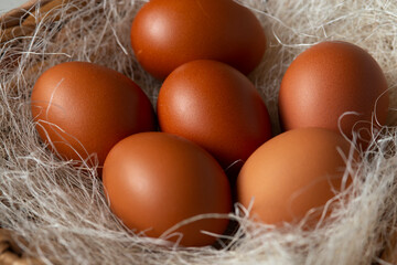 Brown chicken eggs in a wicker basket with straw