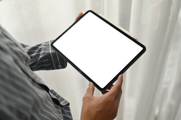 Businessman hands holding digital tablet standing in home office. Blank display for your advertising text message