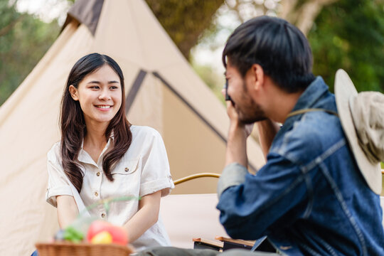 Asian man takes picture of girlfriend..Happy Asian couple taking photo by camera in camping outdoors in nature.