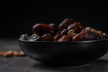 dates and nuts in a bowl on a dark background
