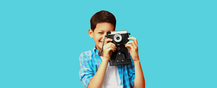 Portrait of happy little boy child with film camera on blue background