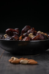 dates and nuts in a bowl on a dark background