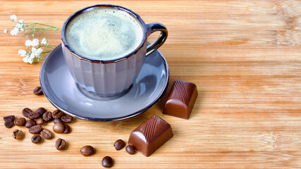 Cup of coffee with cream on wooden table with chocolate praline