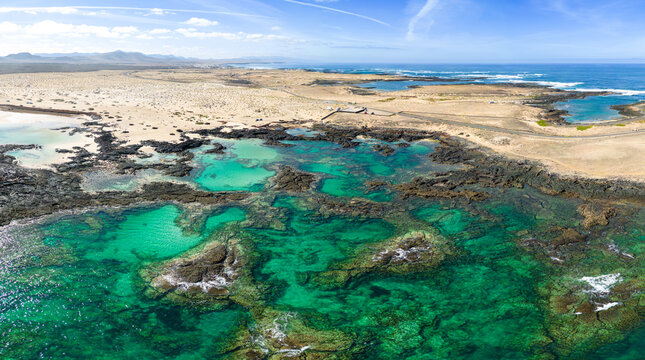 Aerial mid level panoramic view of the natural pools and volcanic rock formations near El Cotillo in Fuerteventura Spain