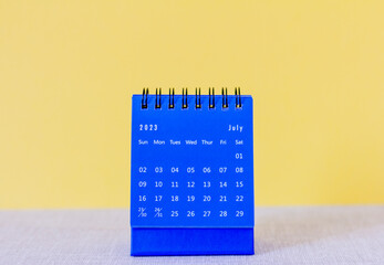 Desk calendar for July 2023 on pink background with copy space.
