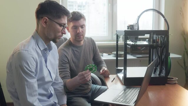 male electronic technician and scientist repairing 3D printer fixing problems cooperating. Additive manufacture. Future work. Team concept.