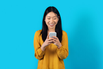 Happy chinese woman using modern smartphone on blue background