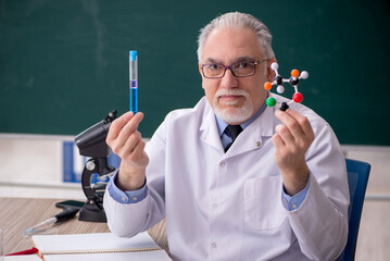 Old male chemist teacher sitting in the classroom