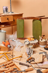 Vertical shot od retro wooden furniture in workshop for repair with variety of instruments and sawdust against brown background. Nobody in shot. Carpenters workplace