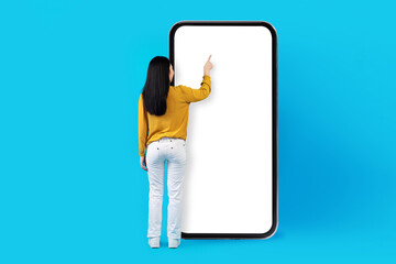 Back view of woman touching blank screen of big smartphone
