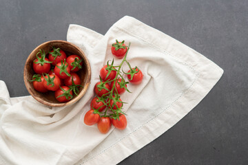 Cherry tomatoes in a wooden bowl with cloth on a black background