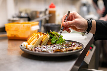 professional chef's hands cooking sliced meat beef brisket with salad and toast in restaurant kitchen