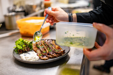 professional chef's hands cooking sliced meat beef brisket with salad and toast in restaurant kitchen