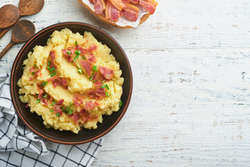 Mashed potatoes. Bacon mashed potatoes with green onion, pepper and cheddar cheese in bowl on old wooden backgrounds. Delicious creamy mashed potatoes. Top view.