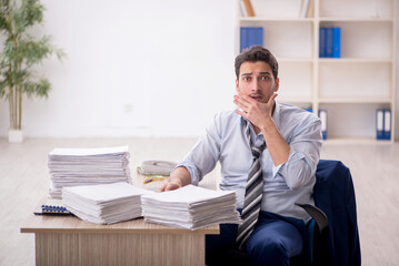 Naklejka premium Young male employee and too much work in the office