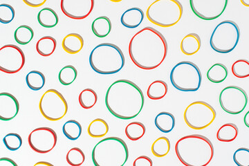 Multi colored rubber bands arranged on white background. Seamless pattern.