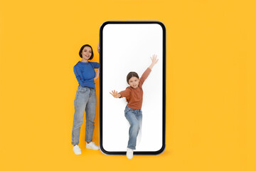 Fototapeta premium Cute Little Girl Walking Out Of Big Blank Smartphone With White Screen