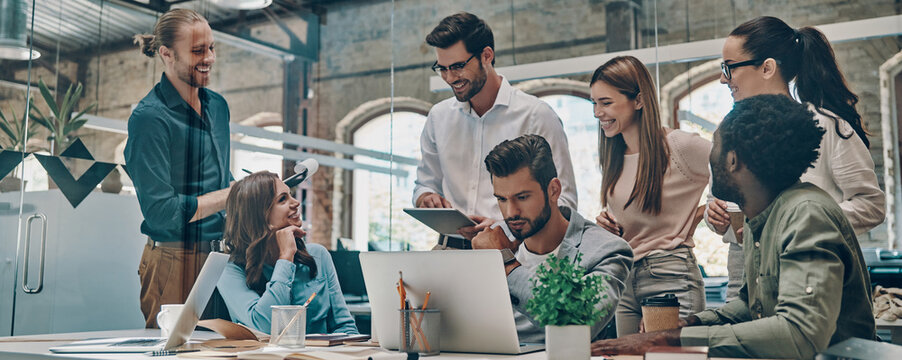 Group of confident people communicating and smiling while working in the office together