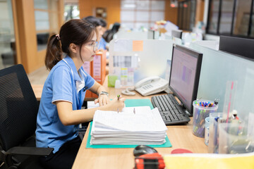 Caucasian female employee wearing glasses working in a company office business plan with computer Dressed in uniform, on the desk were documents, phones, pens, and other gadgets.