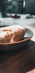 Napoleon cake in a plate on a wooden table near the window