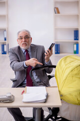 Old male employee looking after new born at workplace