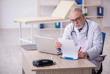 Old male doctor working in the clinic