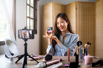 Beauty blogger, young asian woman, girl vlogger posting, showing, reviews cosmetics products while...