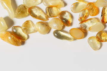 Amber stones on light background with copy space, transparent stone yellow beige color. Natural gemstone mineral material, healing crystal. Top view Amber texture. Nature gems, pieces ancient