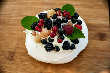 pavlova cakes with summer berries and fruits on a wooden board