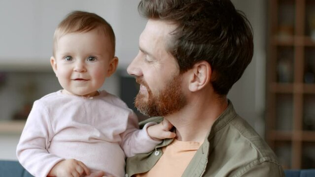 Portrait of adorable little baby girl on dad's hands smiling to camera, loving daddy kissing little girl, slow motion