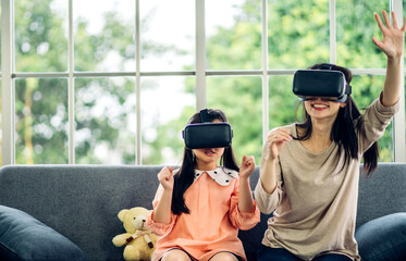Portrait of enjoy happy love asian family mother and asian girl child smiling and having fun using glasses of of technology virtual reality headset.concept of modern VR metaverse technology