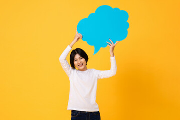 Young Asian woman smiling and holding speech bubble in yellow color isolated studio background - obrazy, fototapety, plakaty