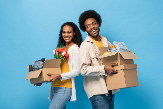 Afro African American couple holding boxes full of household stuff in blue color isolated studio background for moving house concept