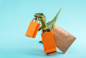 Cute green dinosaur with shopping bags on a blue background. Cute humor shopping concept.