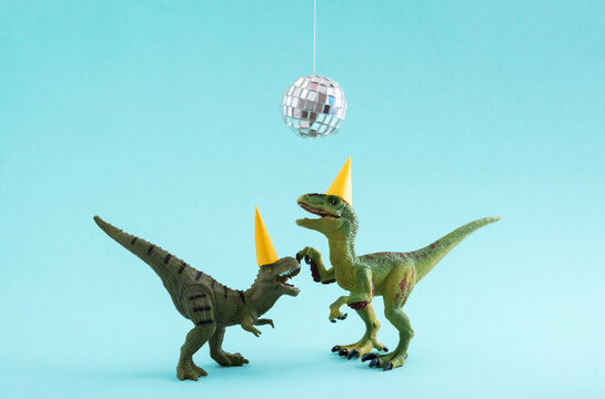 Fototapeta Two cute green dinosaurs dancing under disco ball. Funny idea for birthday card on blue background.